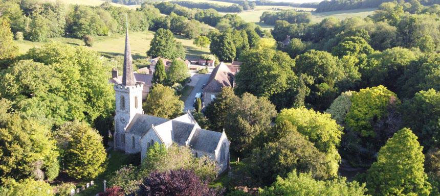 A photograph of a church from above nestled in trees in the countryside