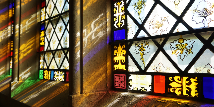 Light shining through a stain glass window with the colours reflecting off the stone.
