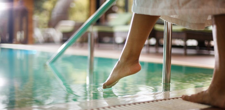 Person dipping their toes in swimming pool